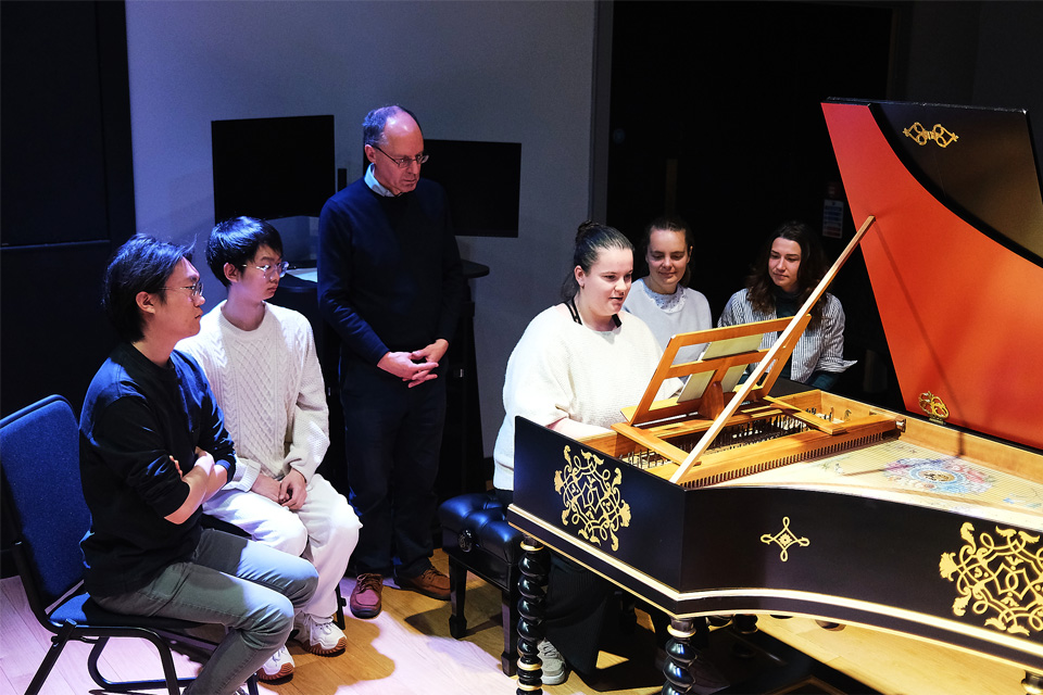 Group of students in a harpsichord in a music lesson in a performance room.